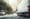 Blurred image of a white delivery van in the city with tree lined streets.