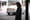Female pedestrian waiting for a rideshare looking at her phone with blurred car driving in the city.