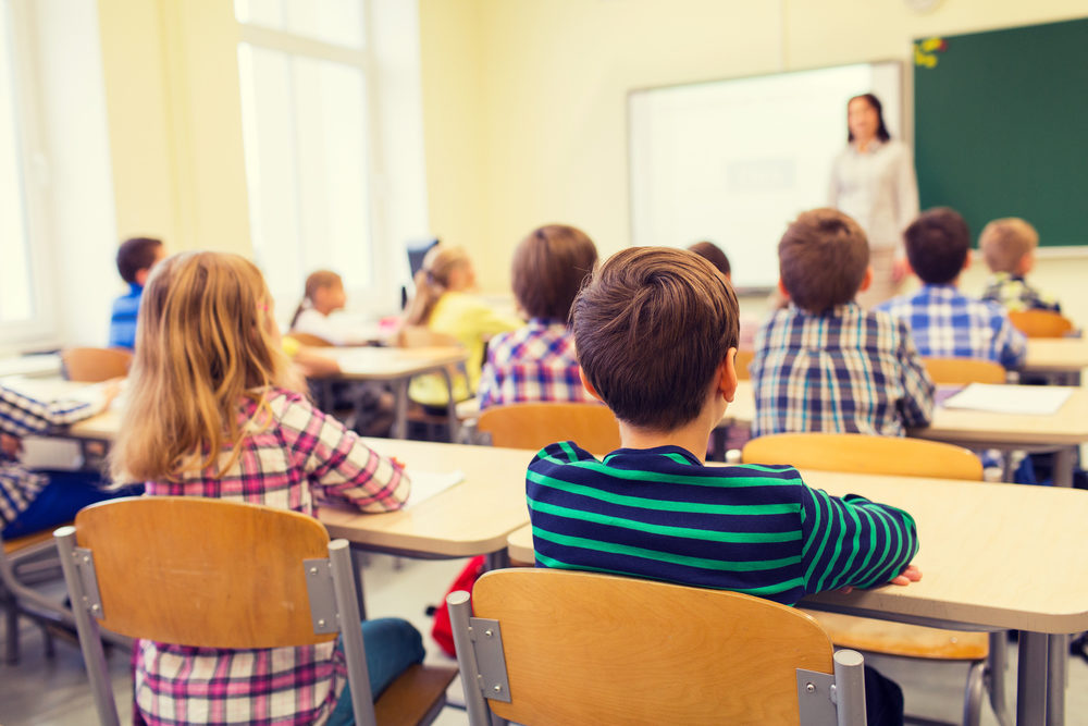 Elementary school children in classroom listening to teacher.