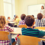 Elementary school children in classroom listening to teacher.