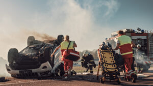 Paramedics and Firefighters attempt to Rescue Injured Victims Trapped in overturned Vehicle at accident scene