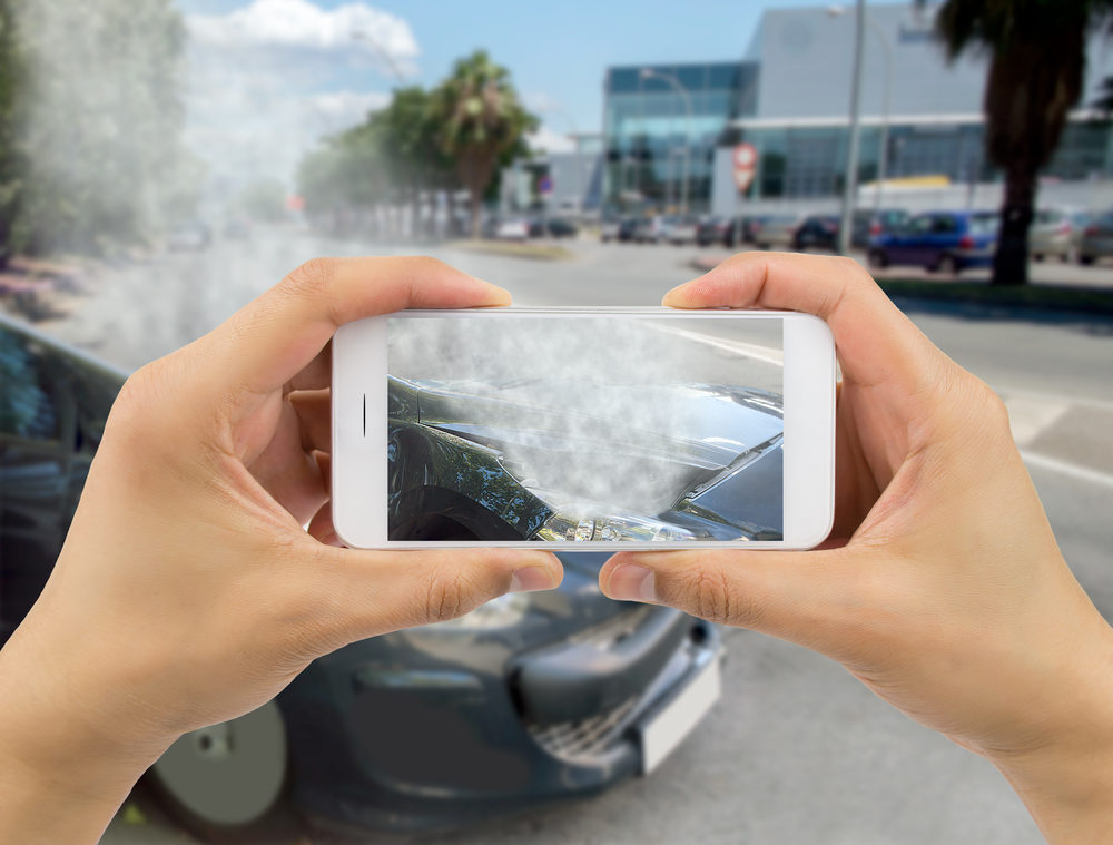 man photographing his car damages for accident insurance at the city road with smart phone