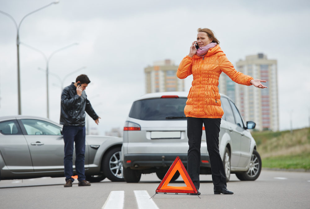 driver man and woman on their phones examining damaged automobile cars after crash accident in city