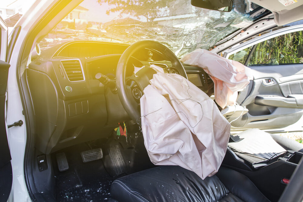 interior of a crashed car after an accident with windshield cracked and airbags deployed