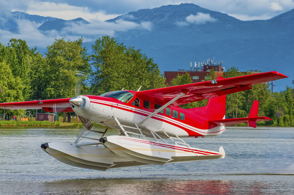 A red and white seaplane takes off on Lake Hood in Anchorage Alaska
