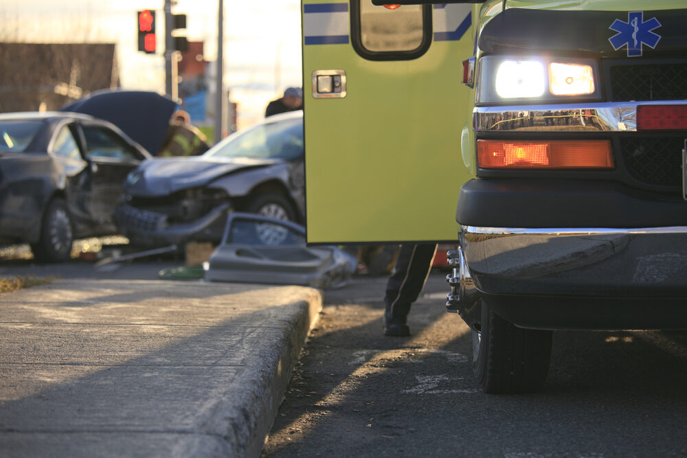 ambulance in forefront with cars crashed on the road behind