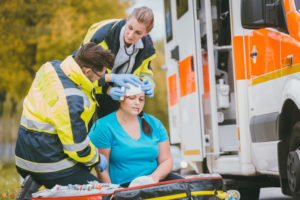 Emergency medics dressing head wound of injured woman after accident