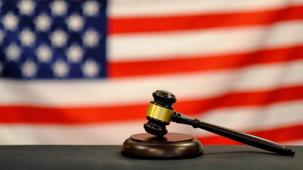 A gavel rests on a banger, with the American flag in the background