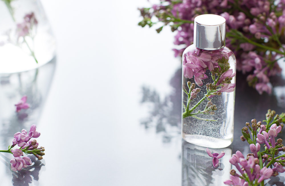 Cosmetic bottle close up with lilac flowers