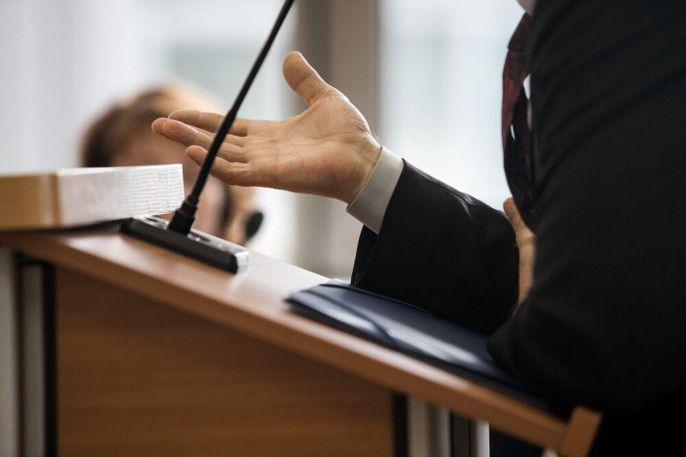 a cropped closeup of an attorney pleading his case in a courtroom