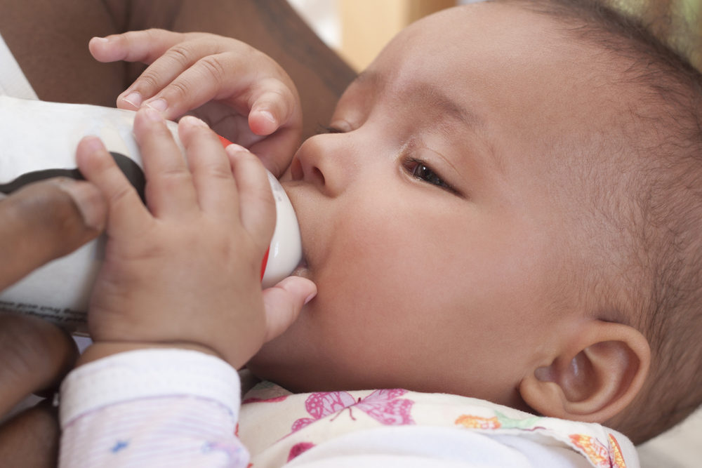 father feeding baby formula in a bottle closeup view