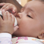 father feeding baby formula in a bottle closeup view