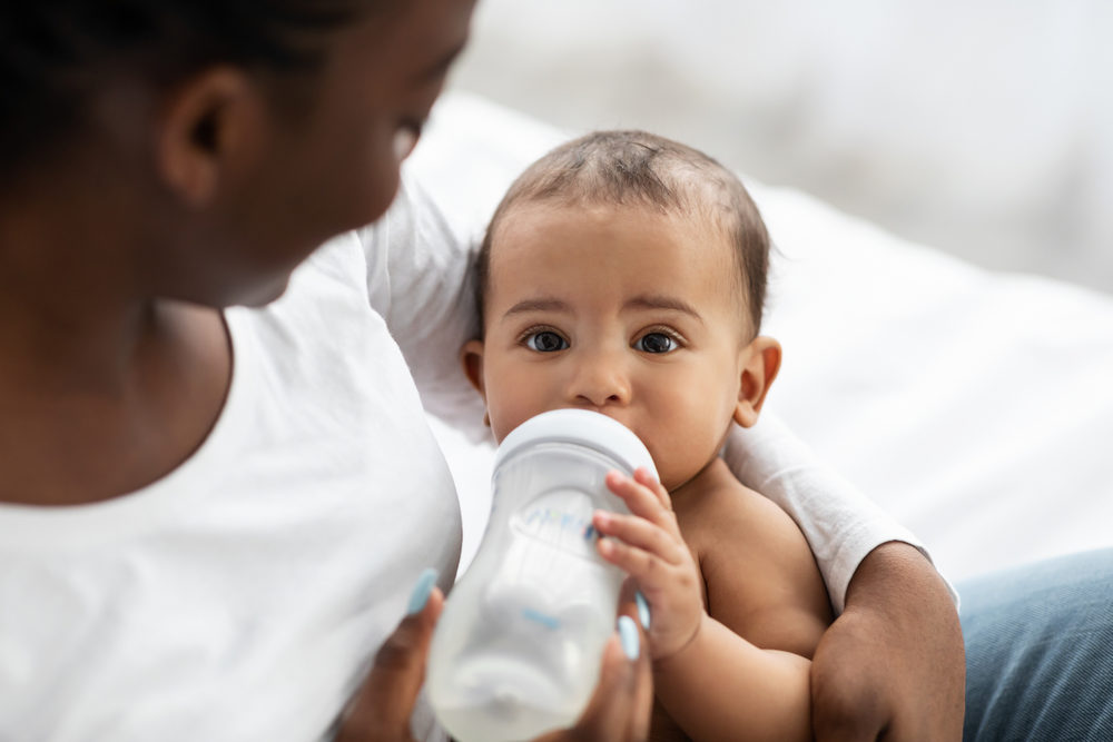 West Virginia Mom Blames Abbott Infant Formula for Twins’ NEC baby being held by mother drinking a bottle