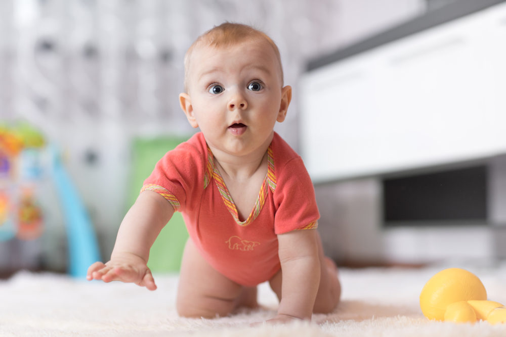 baby boy crawling on the floor in nursery room