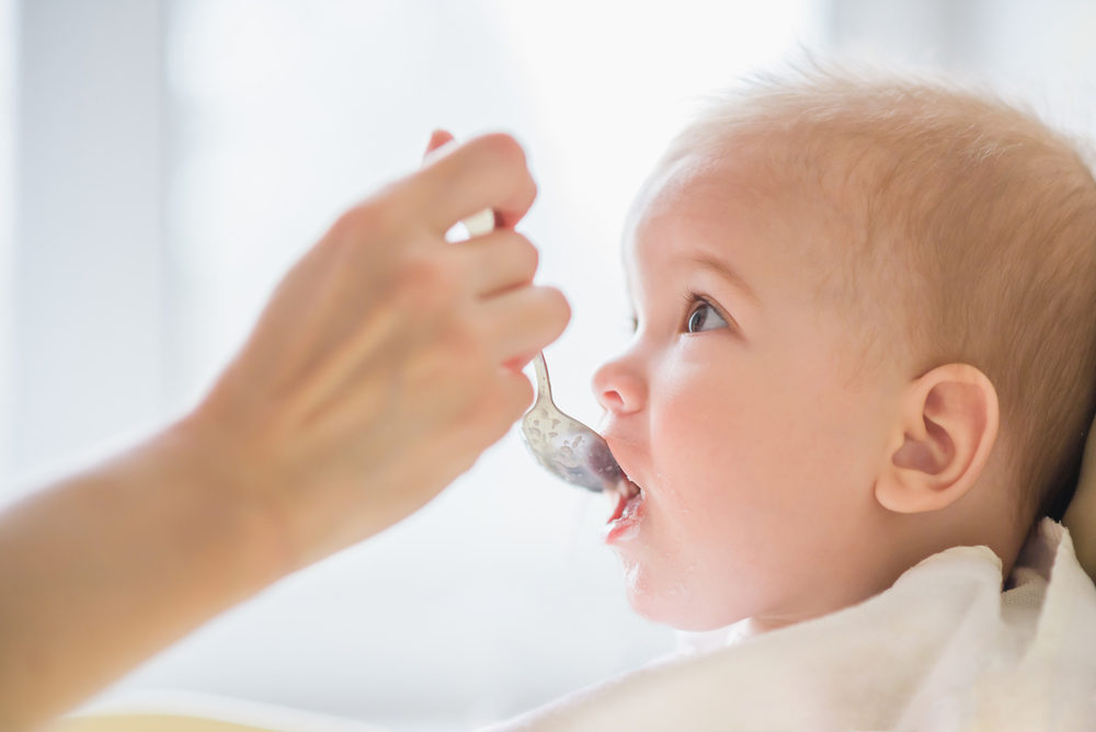 small child sits on a chair and eating with spoon