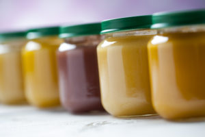 healthy ready-made baby food in jars on a wooden table.