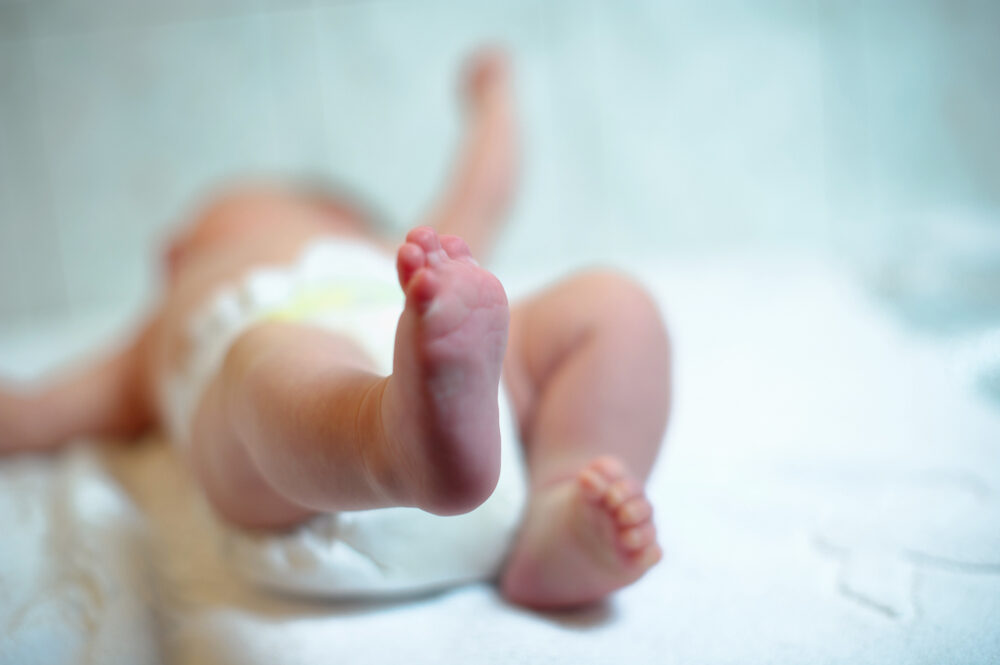 a newborn baby laying on their back with focus on feet