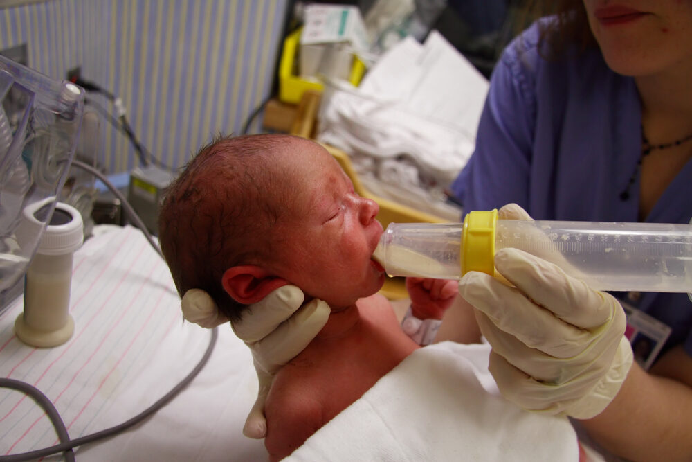 Premature newborn being fed formula from a nurse in hospital