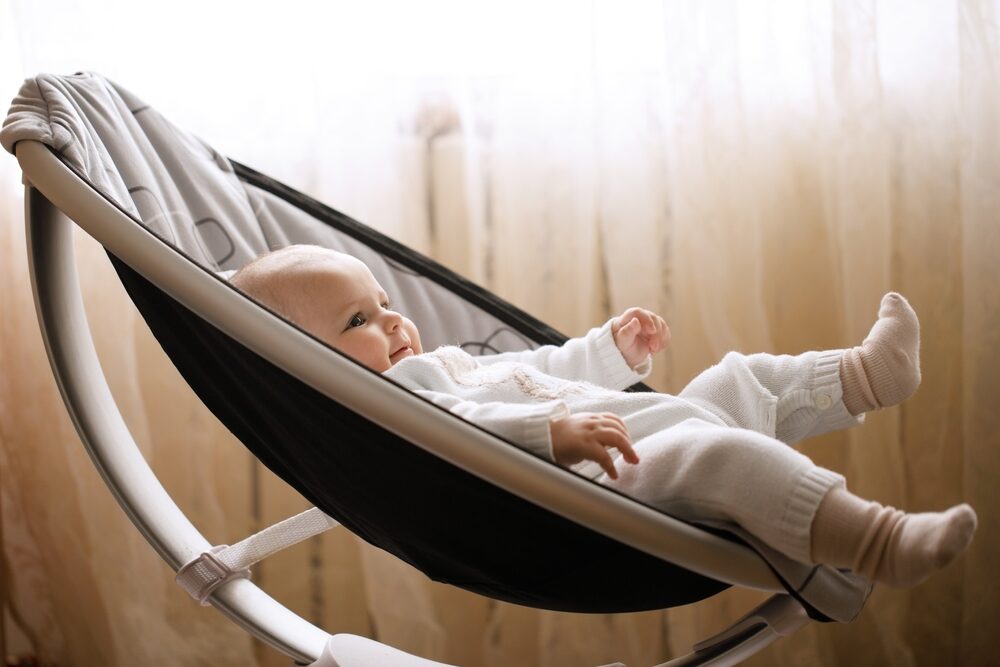 Cute smiling baby laying in swing rocker chair