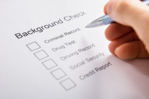 Close-up Of Person Hand Filling Background Check Form
