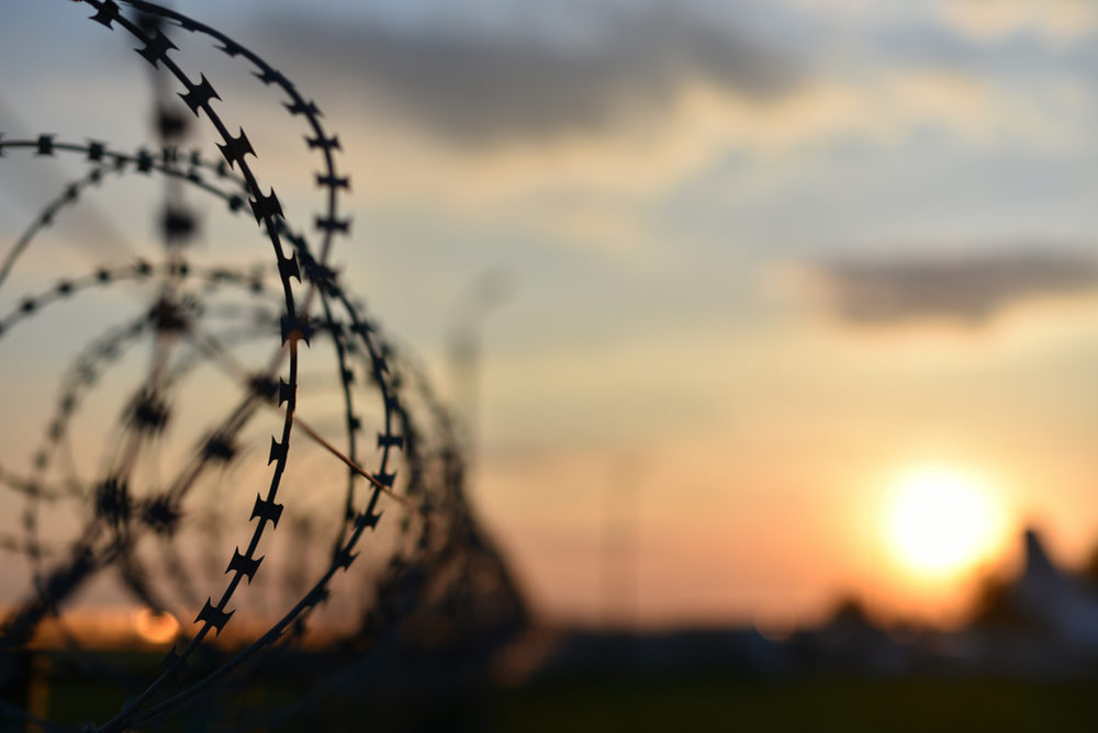 barbed wire of prison fence at sunset