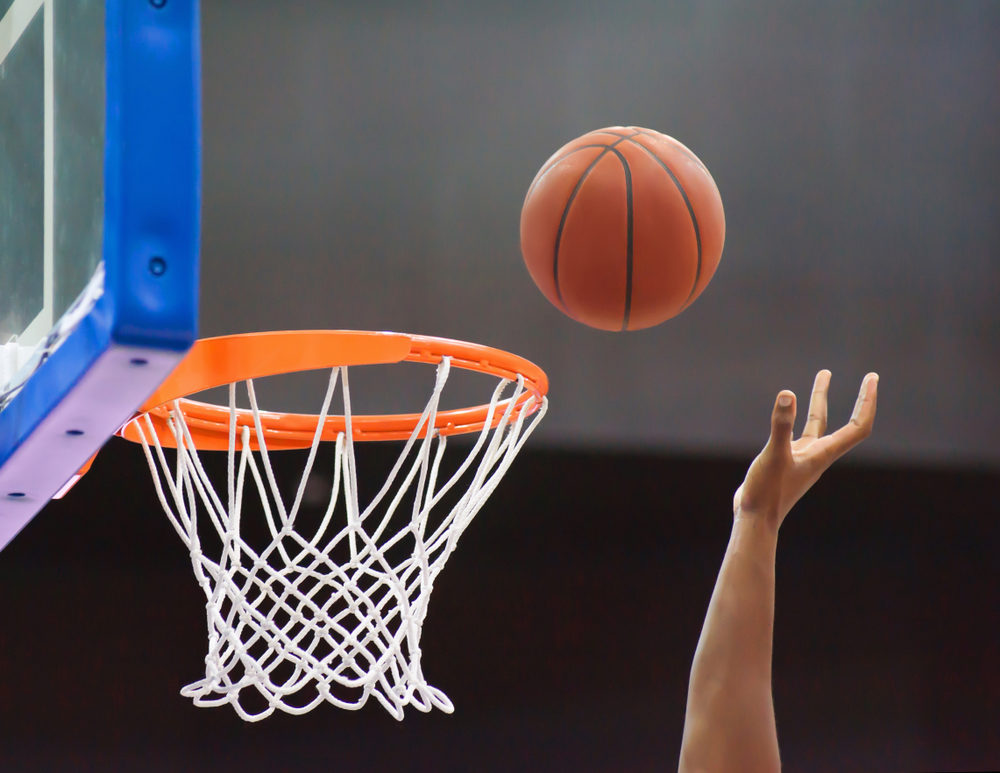 Orange basketball ball flying into the basketball hoop