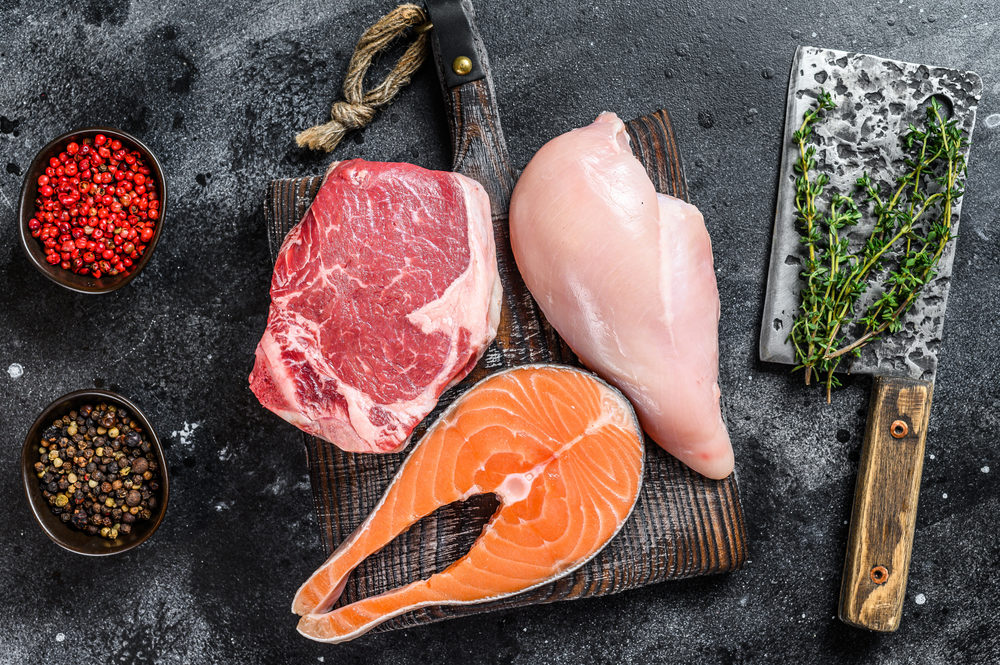 Set of raw meat steaks salmon, beef and chicken on a cutting board.