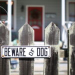 Beware of Dog sign on wooden fence outside of home