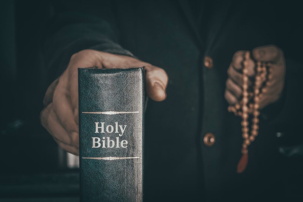 Sacramento Hospice Chaplain, Arthur Earl Apgar, Arrested for Alleged Sexual Assault at Care Facility priest holding a bible and rosary beads