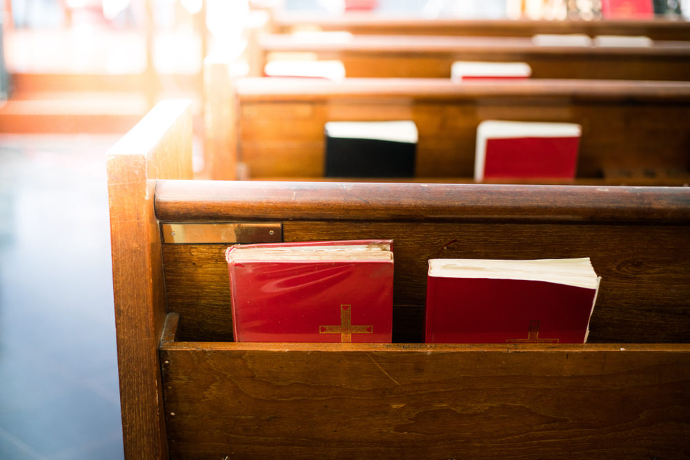 Bibles in wooden bench compartment in church