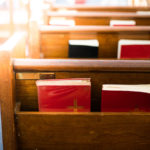 Bibles in wooden bench compartment in church
