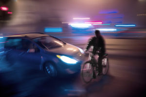 Dangerous city traffic situation with cyclist and car in the city at night in motion blur