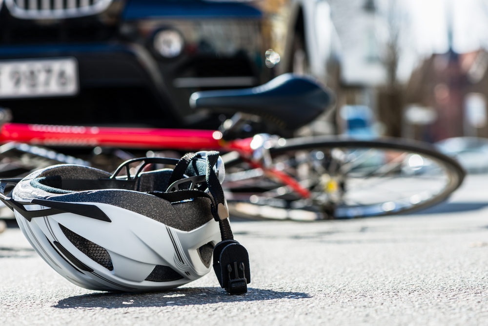 bicycling helmet fallen on the asphalt next to a bicycle after car accident on the street in the city