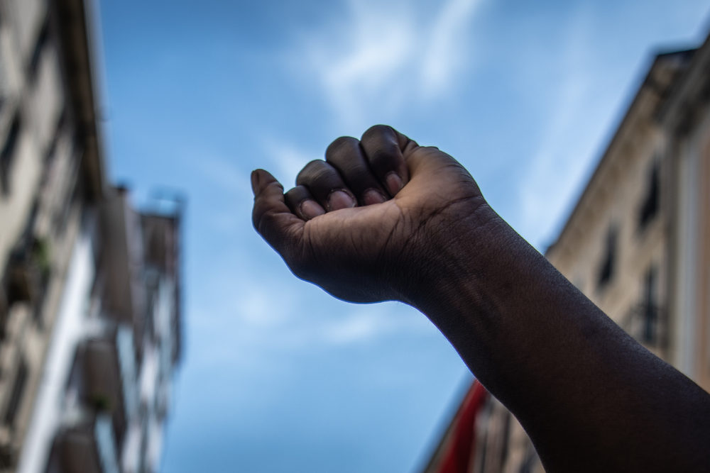a black man raises his fist to the sky during a protest 