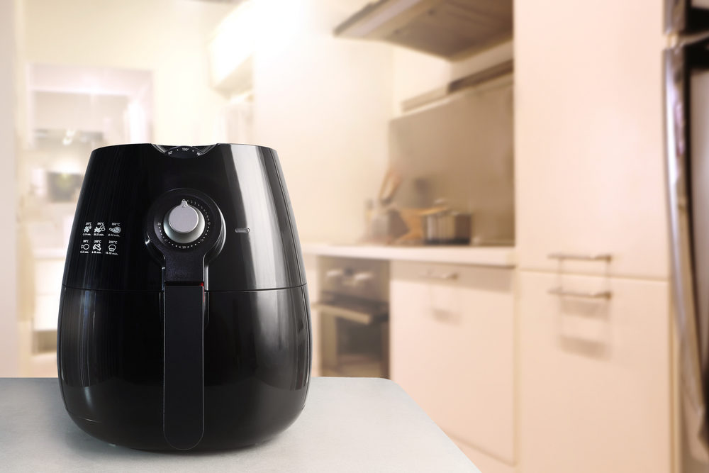 black air fryer appliance on white marble table in the nice interior kitchen