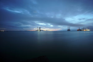 oil platforms offshore under blue skies