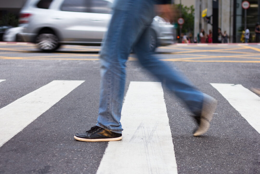blurred pedestrian walking through a crosswalk on a city street