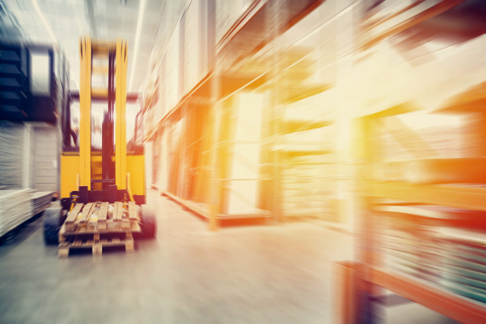 Workplace Violence at Amazon: Middletown Man Arrested for Neck Slashing at New Windsor Distribution Center a blurred warehouse with a forklift for containers.