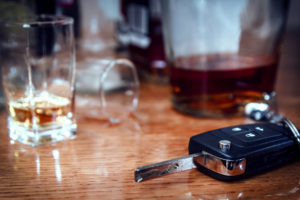 Car key on the bar with spilled alcohol and empty bottles.