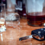 Car key on the bar with spilled alcohol and empty bottles.