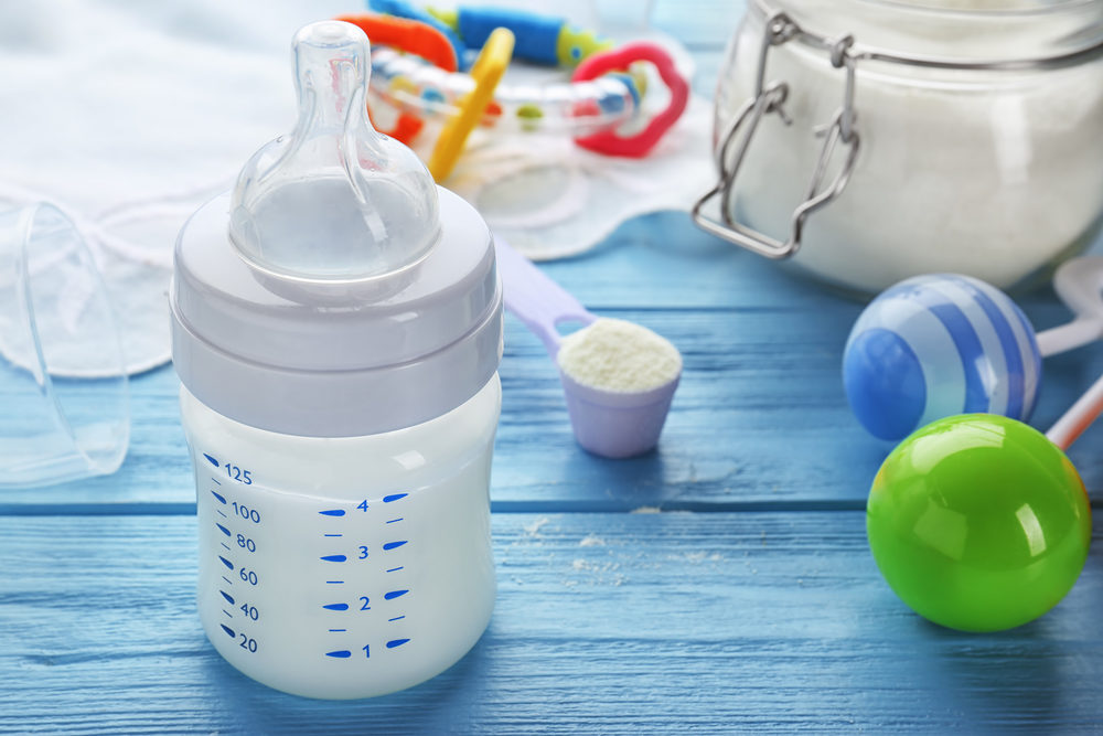 Baby bottle with milk formula on wooden table
