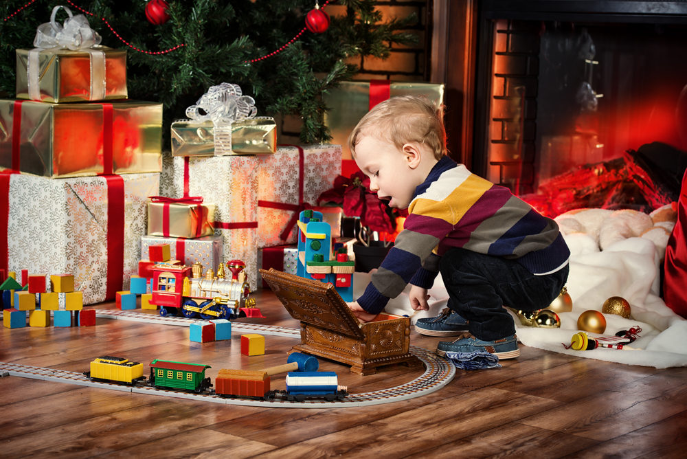 7 Safety Tips for Parents Purchasing Products for Children Little boy playing with toys at home near the fireplace and Christmas tree.