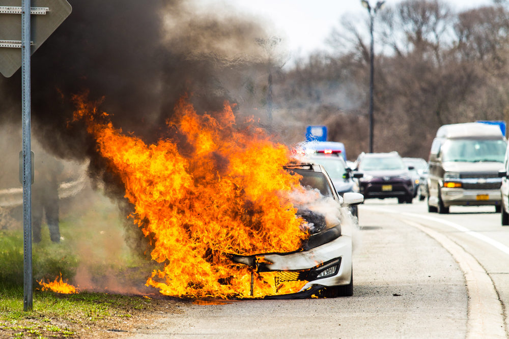 Burning car on fire on a highway road accident at day