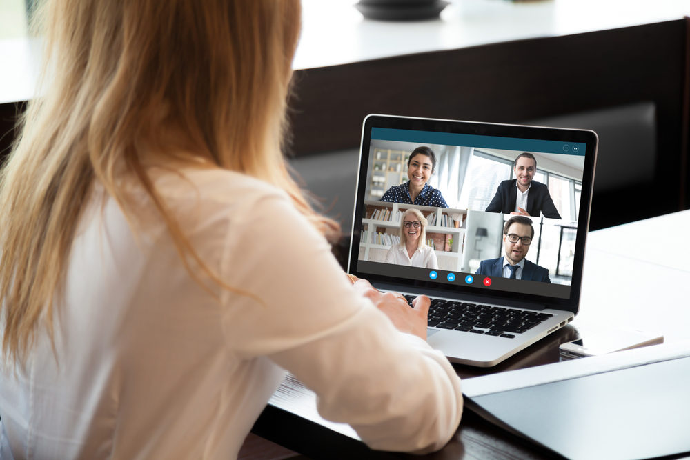 A woman engaged in a video conference call with four coworkers