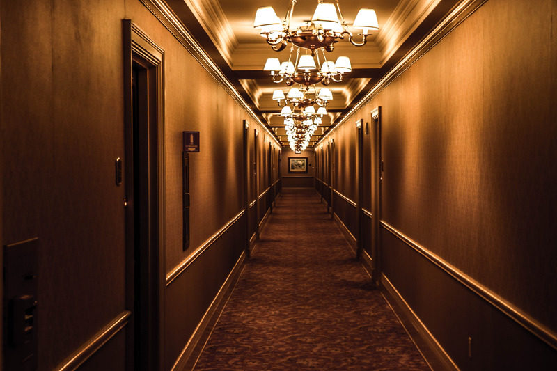 A long interior hotel hallway with ornate ceiling lights