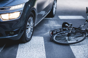 Car standing on the pedestrian path with the downed bicycle