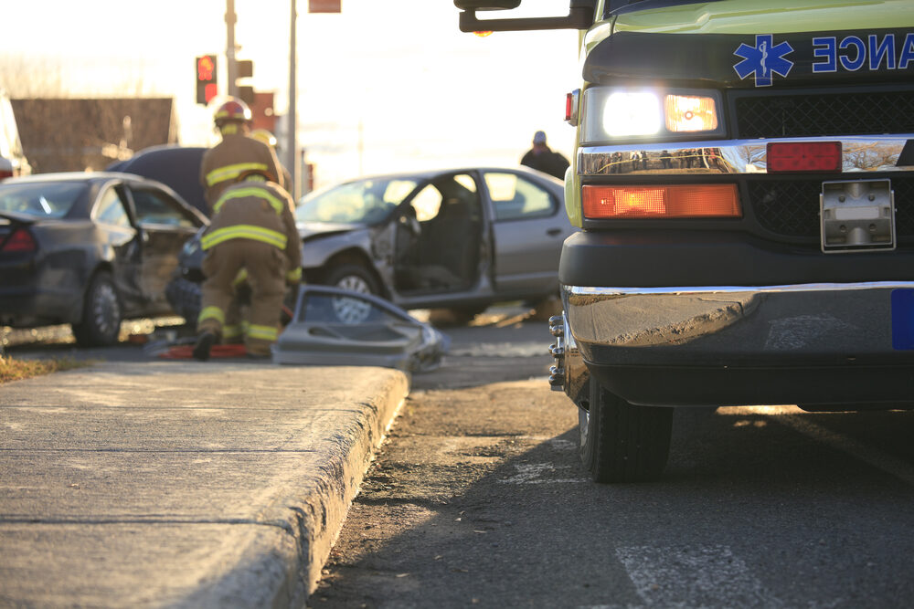 emergency workers at a car accident scene with and ambulance in the forefront