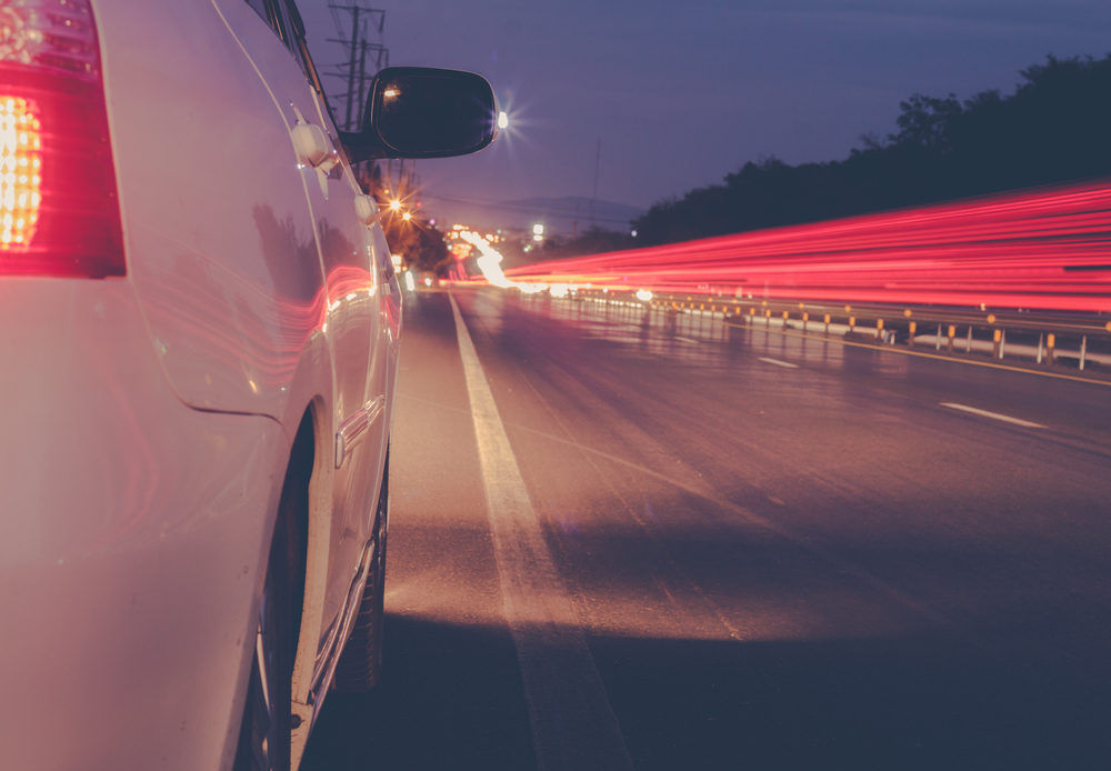 car driving at night with light trails off passing traffic