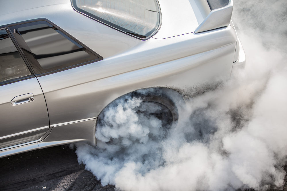 silver rear wheel drive car burning tire on track