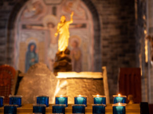 Blue candles burning in catholic church with cross out of focus on wall in background